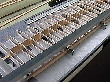 The trailing edge of a wing often is blocked up during construction.  The ribs should be pinned or weighted to keep them in contact with the block.